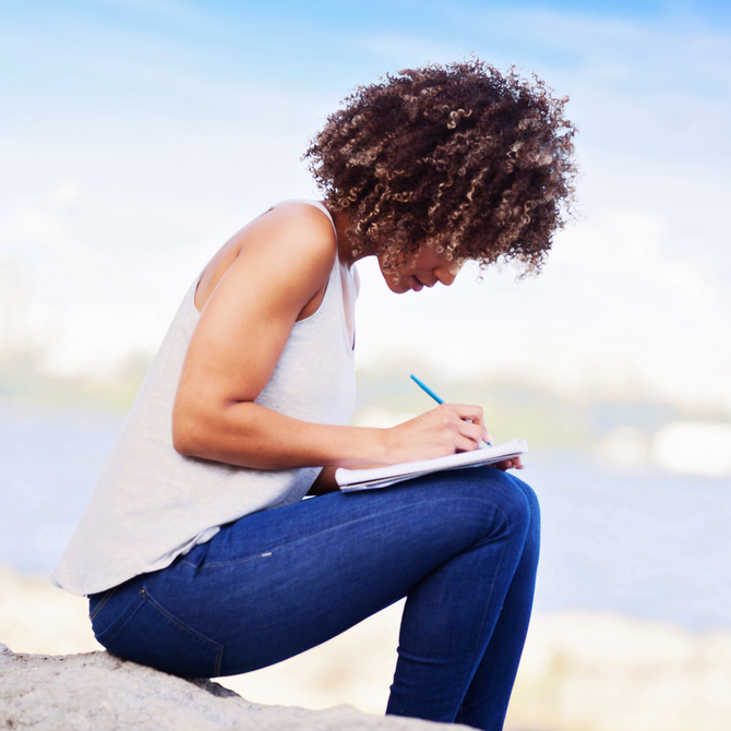 tipos de redação: jovem mulher sentada e escrevendo texto em um caderno